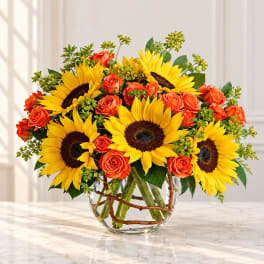 Sunflower and orange rose arrangement in a clear glass vase