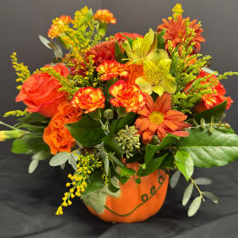 Orange and yellow mixed bouquet in a painted pumpkin container