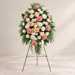 Standing floral wreath with pink and white flowers on a metal easel