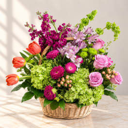 Basket arrangement with pink roses, tulips, and mixed blooms