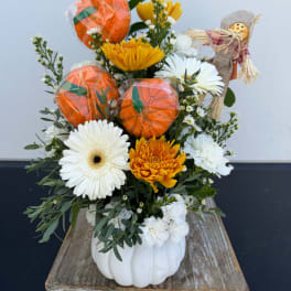 Fall floral arrangement in a white pumpkin container with orange and white blooms