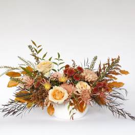 Autumn floral arrangement in a white vase with cream roses and mums