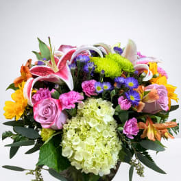 Mixed bouquet with pink lilies, roses, and hydrangea in a glass vase