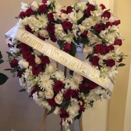 Heart-shaped floral wreath with red and white flowers on an easel