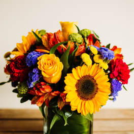 Colorful bouquet in a square glass vase with a sunflower and roses