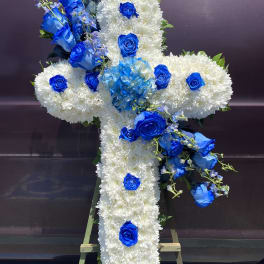 Cross-shaped floral tribute with white chrysanthemums and blue roses