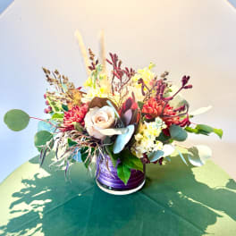 Mixed floral arrangement in a purple vase with cream and red blooms