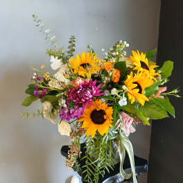 Bouquet of sunflowers, purple blooms, and mixed flowers in a black vase