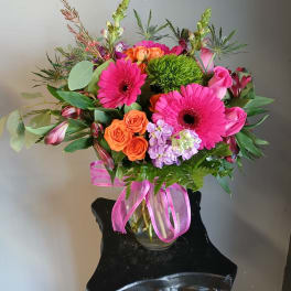Bright mixed bouquet in a glass vase with pink gerberas and orange roses