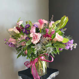 Pink and purple mixed bouquet in a glass vase with a ribbon