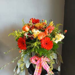 Colorful mixed bouquet in a vase with a pink plaid ribbon