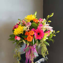 Colorful mixed bouquet in a glass vase with pink, orange, and yellow blooms