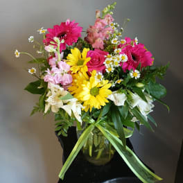 Mixed bouquet of pink, yellow, and white flowers in a glass vase