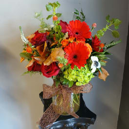 Mixed bouquet of red roses and bright gerbera daisies in a glass vase