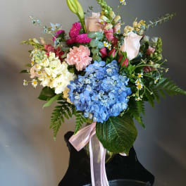 Mixed bouquet with blue hydrangea, roses, carnations, and a pink ribbon
