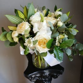 White roses and lilies arranged in a glass vase with eucalyptus