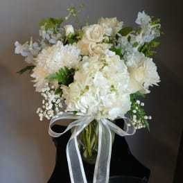 White floral bouquet in a glass vase with a white ribbon