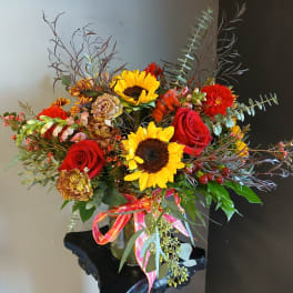 Bouquet of red roses and sunflowers in a glass vase with a ribbon