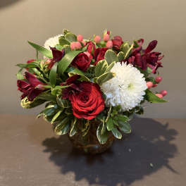 Bouquet of red roses, white chrysanthemums, and burgundy flowers in a glass vase