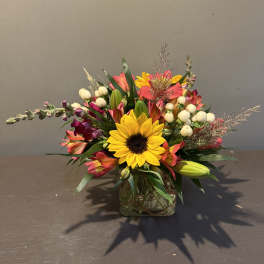 Mixed bouquet with a sunflower in a square glass vase