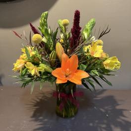 Orange lilies and yellow alstroemeria in a glass vase