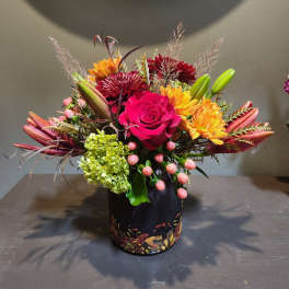 Mixed bouquet with a pink rose, lilies, and chrysanthemums in a black vase