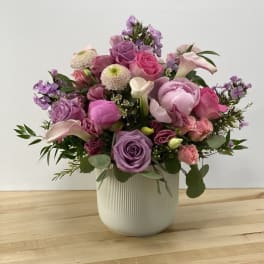 Mixed pink and purple flower arrangement in a white vase