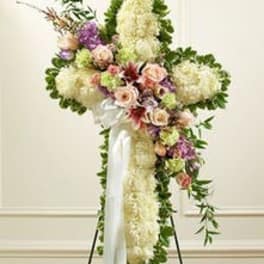 Standing cross-shaped sympathy spray of white flowers with pink and lavender accents on an easel