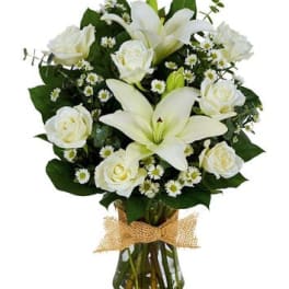 White lilies and roses in a glass vase with burlap ribbon