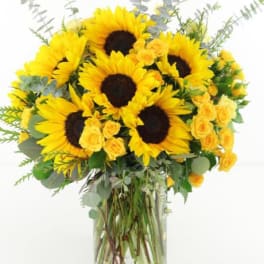 Bouquet of sunflowers and yellow roses in a clear glass vase