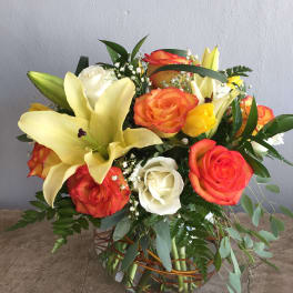 Bouquet of orange and white roses with yellow lilies in a woven basket