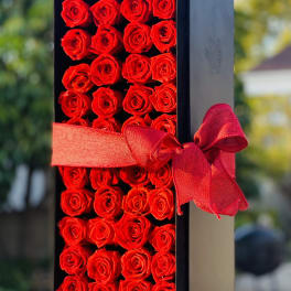 Black box filled with red roses and tied with a red ribbon