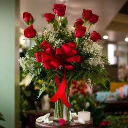 Red roses in a glass vase with a red ribbon bow
