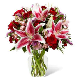 Bouquet of pink lilies and red roses in a clear glass vase