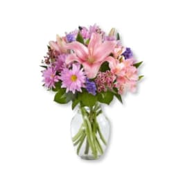 Pink and purple mixed flowers arranged in a clear glass vase