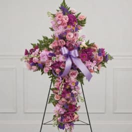 Cross-shaped floral arrangement in pink and purple flowers with a lavender ribbon