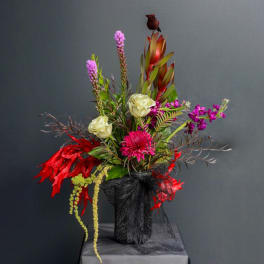 Tall floral arrangement with pink, white, and red blooms in a black vase
