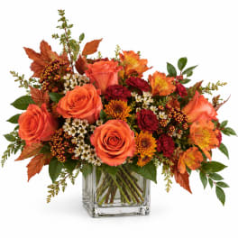 Orange and red mixed bouquet in a clear glass vase
