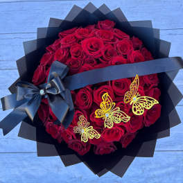 Bouquet of red roses wrapped in black paper with a black ribbon and butterfly accents