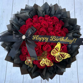 Red rose bouquet with black wrapping, a birthday ribbon, and butterfly decorations