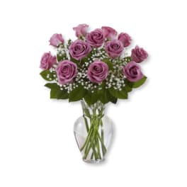 Purple roses in a clear glass vase with baby's breath
