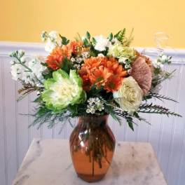 Orange and white flower arrangement in an amber glass vase