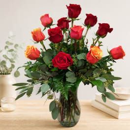 Red and orange roses arranged in a clear glass vase