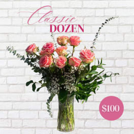 Pink roses arranged in a clear glass vase with greenery