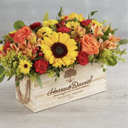 Mixed flower arrangement in a wooden crate with sunflowers and roses