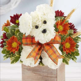 White dog-shaped floral arrangement with orange daisies and a plaid bow in a wooden box