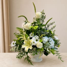 White and pale yellow floral arrangement in a white pedestal vase