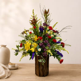 Colorful mixed flower arrangement in a rustic wooden vase