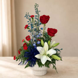 Red roses and white lilies in a white vase with a blue ribbon
