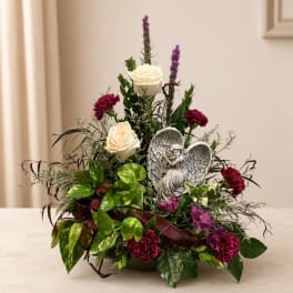 Floral arrangement with white roses, burgundy carnations, and an angel figurine